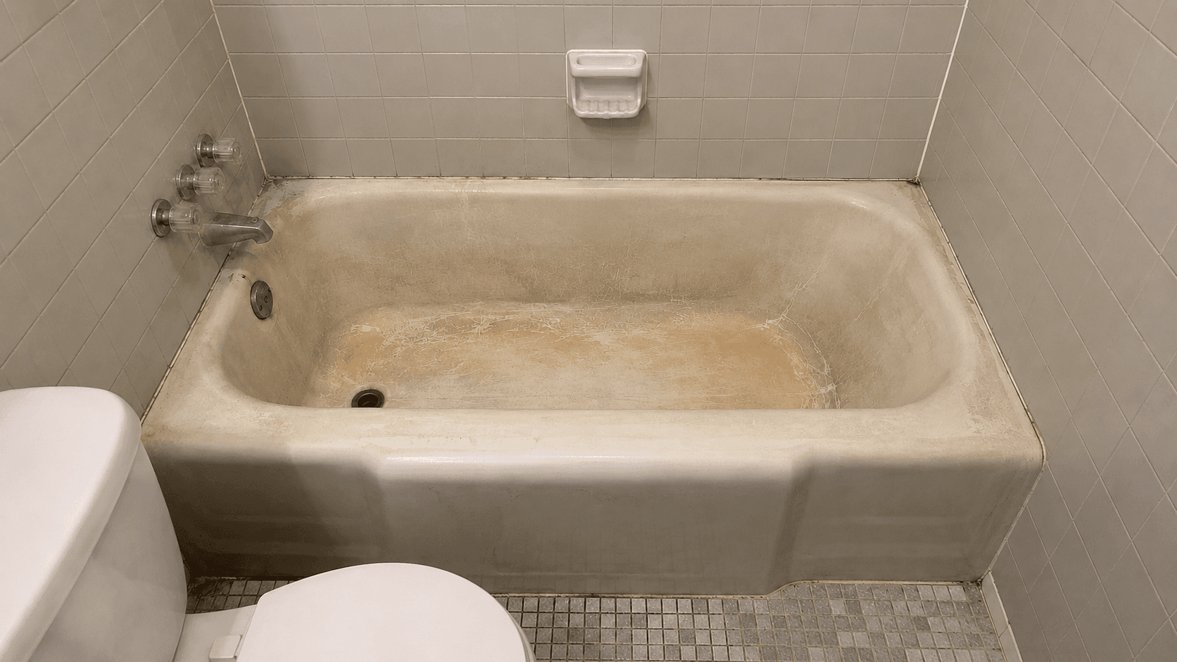 Bathtub before reglazing with worn beige surface, staining, and dated finish